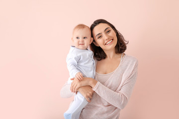 cute baby with mother on color background