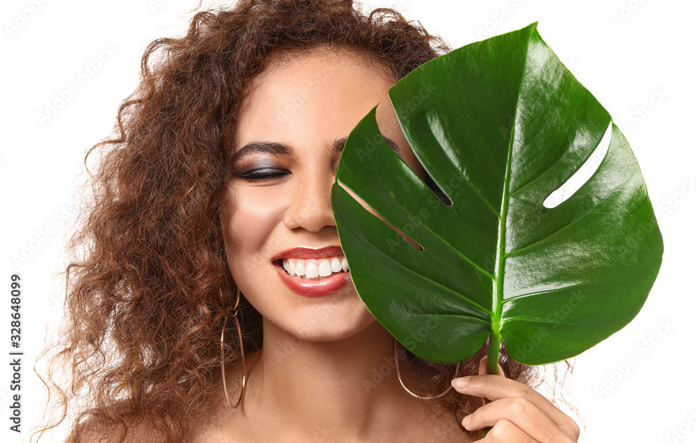 Beautiful African-American woman with tropical leaf on white background