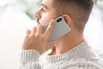 Canvas Print - Young man talking by mobile phone at home