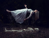 Fototapeta Konie - Levitation image of a woman rising from a skeleton on dead leaves