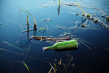 Green Glass Bottle In Blue Lake Water