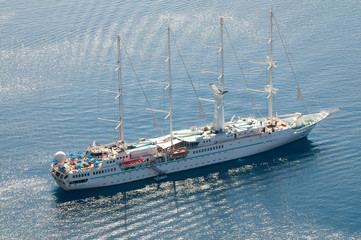 Wall Mural - View of large old-fashioned sailboat moored with bare masts floating on the Mediterranean Sea off Santorini, Greece