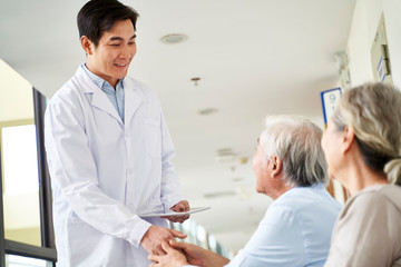 Poster - young asian doctor shaking hands with senior patient