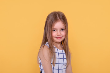 shot of a little smiling girl with long blonde hair against yellow background with copy space in stu