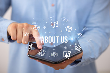 Poster - Businessman holding a foldable smartphone with ABOUT US inscription, social media concept