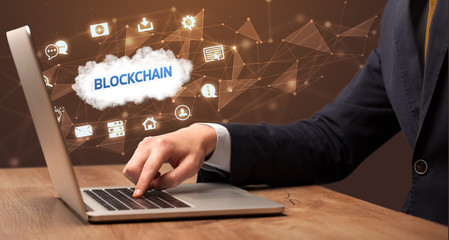 businessman working on laptop with blockchain inscription, modern technology concept