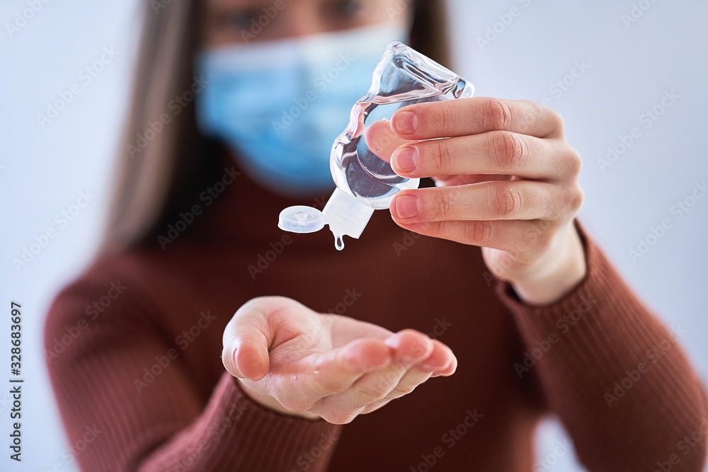 Woman in medical protective mask applying an antibacterial antiseptic gel for hands disinfection and health protection during during flu virus outbreak. Coronavirus quarantine and novel covid ncov - obrazy, fototapety, plakaty 