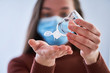 © Goffkein - Woman in medical protective mask with an antibacterial antiseptic gel for hands disinfection from bacteria during flu virus outbreak, coronavirus epidemic and infectious diseases. Covid ncov
