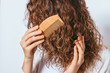 Close-up young woman combing her curly hair