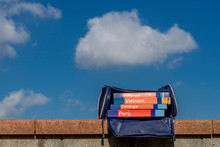 Group Of Printed Tourist Guides In A Bag Against The Blue Sky With Some Clouds