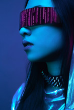 Neon Portrait Of A Girl Of Asian Appearance, Dressed In Futuristic Clothes And Glasses. Neon Blue And Pink Light. Virtual Reality Glasses And Binary Code In Them.