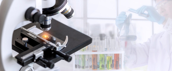 Wall Mural - laboratory concept; close up of microscope with a blurred picture of the scientist is researching in