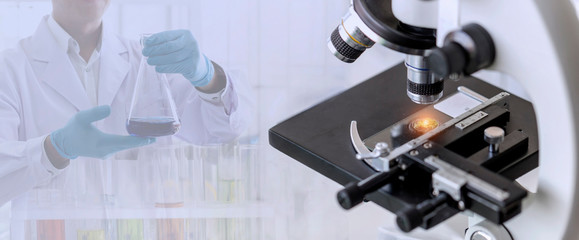 Laboratory concept; close up of microscope with a blurred picture of the scientist is researching in laboratory