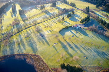 Aerial view of links golf course during summer showing green and bunkers at driving range club house