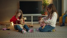Beautiful Twin Sisters Enjoying Leisure Together Playing With Favorite Dolls Indoors, Little Preschool Female Children Kids Sitting On Floor In Modern Living Room Girls Interesting Game At Cozy Home