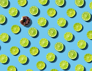 Wall Mural - One out unique donut surrounded by limes - flat lay