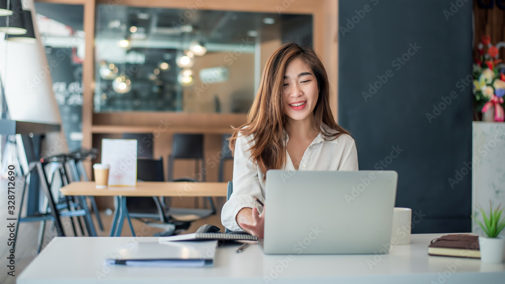 Charming asian businesswoman sitting working on laptop in office. - obrazy, fototapety, plakaty 