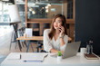 © amnaj - Young asian businesswoman beautiful charming smiling and talking on the mobile phone in the office.