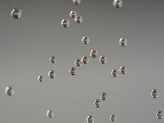 closeup of air bubbles on water glass with gray background