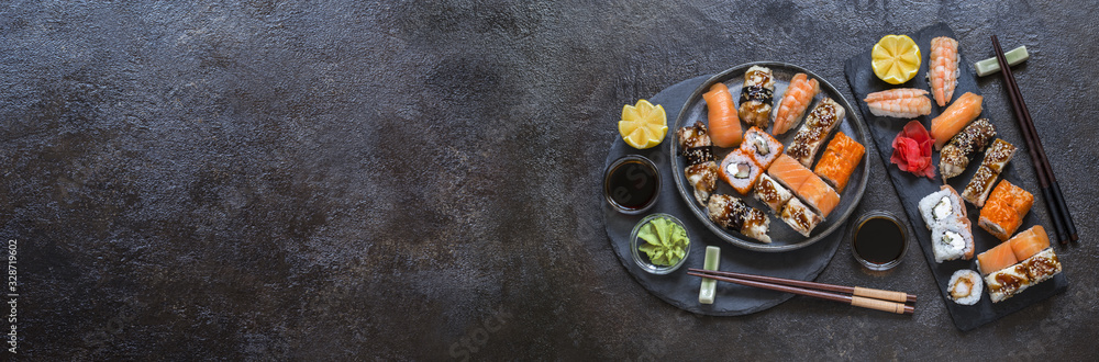 sushi rolls with rice and fish, soy sauce on a dark stone background - obrazy, fototapety, plakaty 