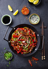 Wall Mural - Beef and vegetables stir fry in a pan. Grey background. Top view.