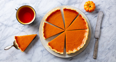 Wall Mural - Pumpkin pie on plate with cup of tea. Marble background. Top view.