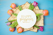 Jewish holiday Passover greeting card with matzah and tulip flowers on wooden table. Pesach background.