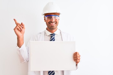 Canvas Print - Young chemist man wearing security helmet holding signboard over isolated background very happy pointing with hand and finger to the side