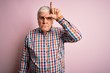 Senior handsome hoary man wearing casual colorful shirt over isolated pink background making fun of people with fingers on forehead doing loser gesture mocking and insulting.