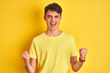 teenager boy wearing yellow t-shirt over isolated background celebrating surprised and amazed for su