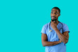 © Carlos David - Portrait of a friendly male doctor or nurse wearing blue scrubs uniform thinking and looking to side at copy space