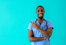 Portrait Of A Smiling Male Doctor Or Nurse Pointing With Finger  To Side At Studio Copy Space And Looking At Camera
