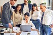 © Krakenimages.com - Group of business workers smiling happy and confident. One of them sitting and partners standing around. Working together with smile on face looking at the laptop at the office