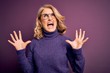 © Krakenimages.com - Middle age beautiful blonde woman wearing casual purple turtleneck sweater and glasses crazy and mad shouting and yelling with aggressive expression and arms raised. Frustration concept.
