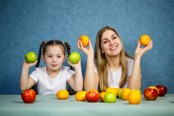 Little girl and mom play with fruits and fool around. They are wearing t-shirts