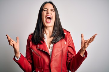 Sticker - Young brunette woman with blue eyes wearing red casual jacket over white background crazy and mad shouting and yelling with aggressive expression and arms raised. Frustration concept.