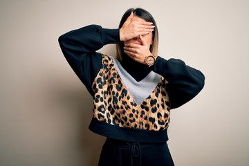 Poster - Young beautiful woman wearing casual sweatshirt standing over isolated white background Covering eyes and mouth with hands, surprised and shocked. Hiding emotion