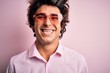 © Krakenimages.com - Young handsome man wearing glasses with heart form over isolated pink background with a happy and cool smile on face. Lucky person.