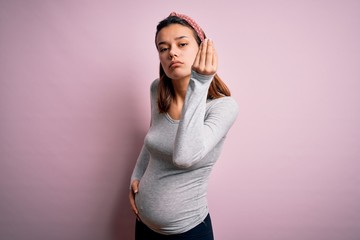 Young beautiful teenager girl pregnant expecting baby over isolated pink background Doing Italian gesture with hand and fingers confident expression