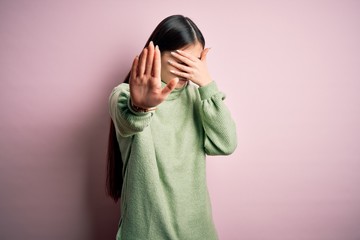 Poster - Young beautiful asian woman wearing green winter sweater over pink solated background covering eyes with hands and doing stop gesture with sad and fear expression. Embarrassed and negative concept.