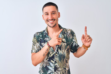 Sticker - Young handsome man wearing Hawaiian summer shirt over isolated background smiling and looking at the camera pointing with two hands and fingers to the side.