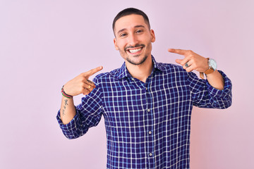 Poster - Young handsome man standing over isolated background smiling cheerful showing and pointing with fingers teeth and mouth. Dental health concept.