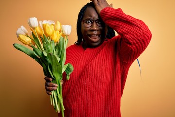 Poster - Young african american plus size woman with braids holding bouquet of yellow tulips flower surprised with hand on head for mistake, remember error. Forgot, bad memory concept.