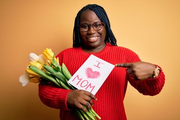 Sticker - Plus size african american woman holding love mom message and tulips on mothers day very happy pointing with hand and finger