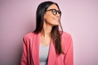 © Krakenimages.com - Young beautiful brunette businesswoman wearing jacket and glasses over pink background looking away to side with smile on face, natural expression. Laughing confident.