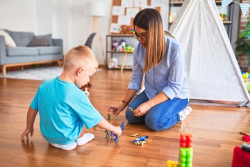 Young caucasian child playing at playschool with teacher. Playing with toy soldiers at playroom around toys.