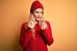 © Krakenimages.com - Young beautiful blonde woman wearing casual sweater and wool cap over white background doing money gesture with hands, asking for salary payment, millionaire business