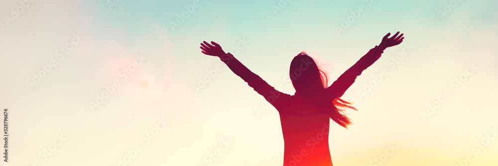 Happy woman sihouette with arms raised up in success on sunset glow sunshine banner panorama. Wellness, financial freedom, healthy life concept background. - obrazy, fototapety, plakaty 