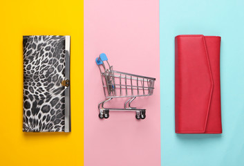 Shopping trolley with wallets on colored background. Top view. Minimalism shopping concept. Flat lay