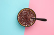 Chocolate cereal balls with milk and spoon in bowl on pink blue pastel background. Concept for a healthy diet. Top view
